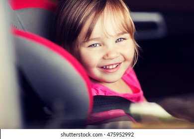 Transport, Safety, Childhood Road Trip And People Concept - Happy Little Girl Sitting In Baby Car Seat