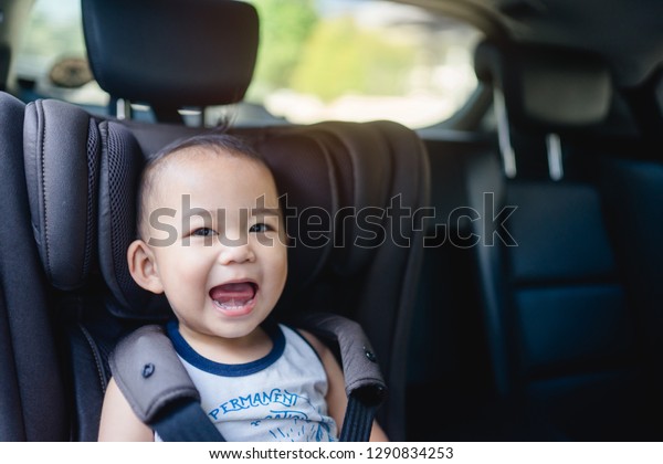 Transport, safety, childhood road trip and people
concept - Happy baby boy sitting in baby car seat or booster seat,
Child in auto baby seat in car, Asian boy in summer vacation to
travel with family.