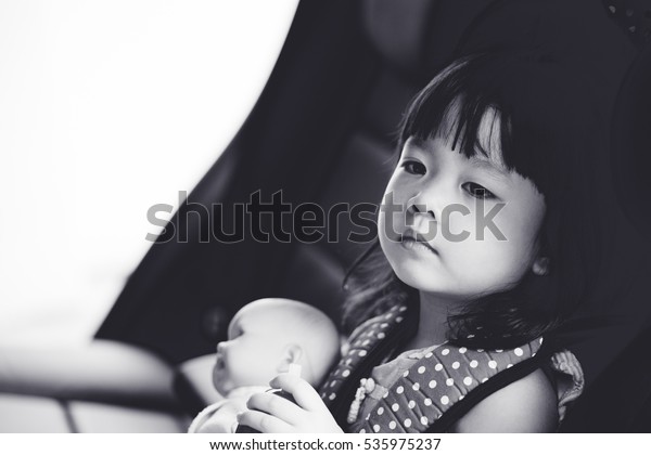 Transport,\
safety, childhood road trip and people concept - happy little girl\
sitting in booster seat.black and white\
tone.