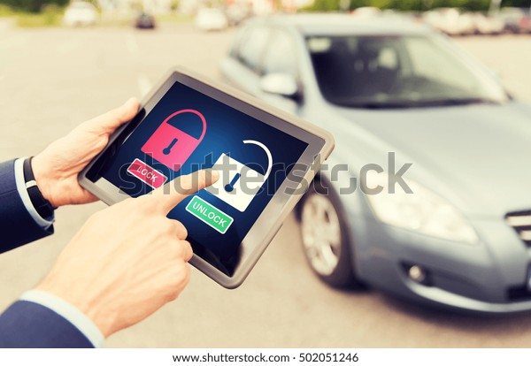 transport, safety, security, technology and\
people concept - close up of male hands with lock and unlock icon\
on tablet pc computer screen and car\
outdoors