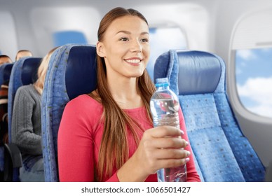 Transport, Tourism And People Concept - Happy Young Woman With Water Bottle In Plane Over Porthole Background