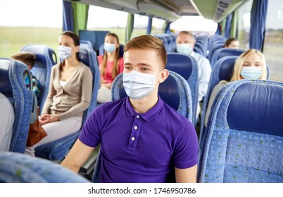 transport, tourism, road trip and people concept - young man wearing face protective medical mask for protection from virus disease sitting in travel bus or train