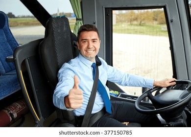 Transport, Tourism, Road Trip And People Concept - Happy Driver Driving Intercity Bus And Snowing Thumbs Up