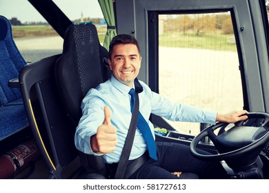 transport, tourism, road trip and people concept - happy driver driving intercity bus and snowing thumbs up