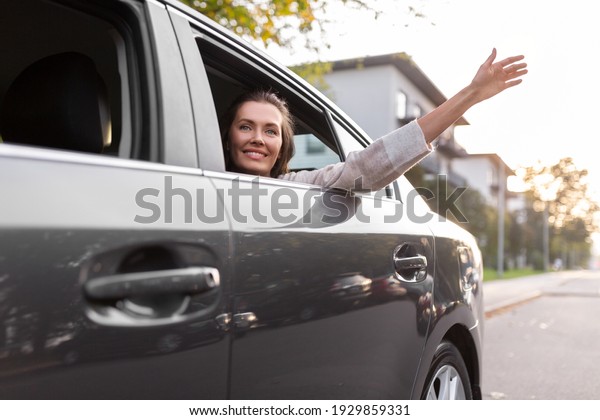 transport, vehicle and\
people concept - happy smiling woman or female passenger waving\
hand in taxi car