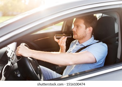 Transport, Vehicle And People Concept - Smiling Man Or Driver Driving Car And Recording Message Using Voice Command Recorder On Smartphone