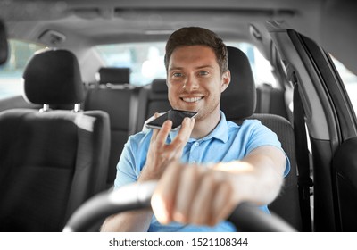 Transport, Vehicle And People Concept - Smiling Man Or Driver Driving Car And Recording Message Using Voice Command Recorder On Smartphone