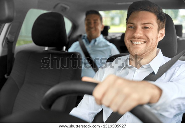 transport, vehicle and taxi concept -\
happy smiling male driver driving car with\
passenger