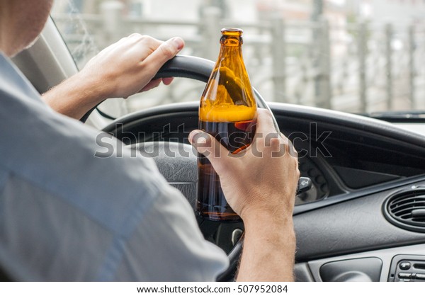 transportation, alcohol,\
vehicle and people concept - close up of man drinking alcohol while\
driving car