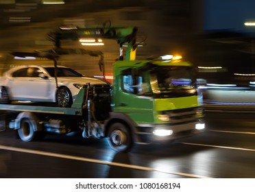 Transportation Of The Car On The Tow Truck In The City At Night. Blurred Motion