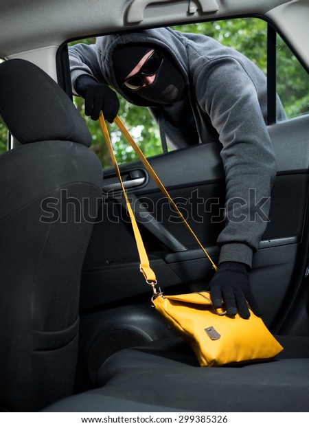 Transportation crime concept .Thief stealing bag from\
the car