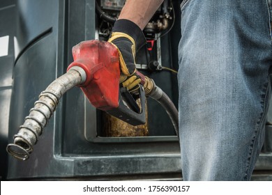 Transportation Industry Theme. Trucker with Diesel Pump Nozzle in His Hand Preparing to Fueling Up His Semi Truck. Close Up Photo. 