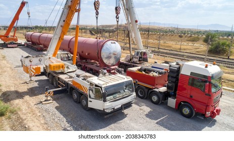 Transportation of oversized cargo.Two truck cranes load an oversized cistern onto a transport truck. - Shutterstock ID 2038343783