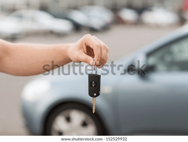transportation and ownership concept - man with\
car key outside