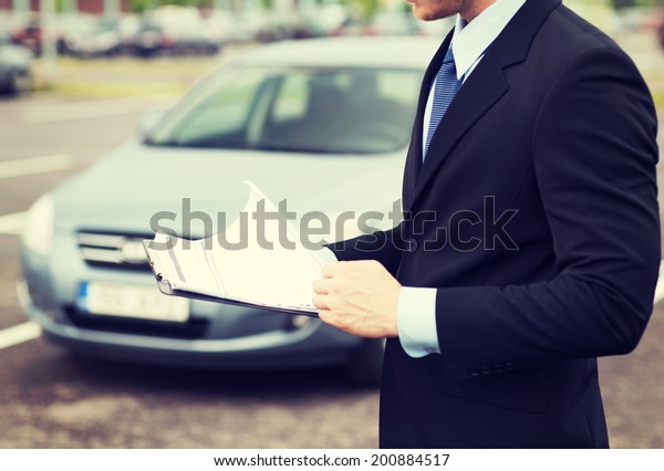 transportation and ownership concept - man with\
car documents\
outside