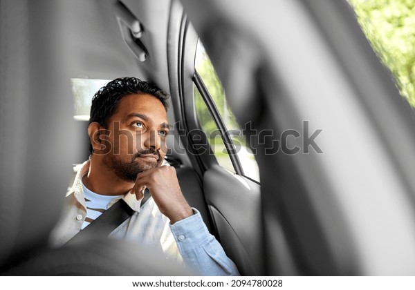 transportation and people concept - dreaming indian\
male passenger in taxi\
car