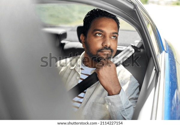 transportation and people concept - dreaming indian\
male passenger in taxi\
car