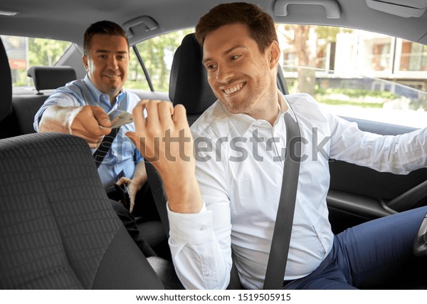 transportation, taxi and payment concept - male\
car driver taking money from\
passenger