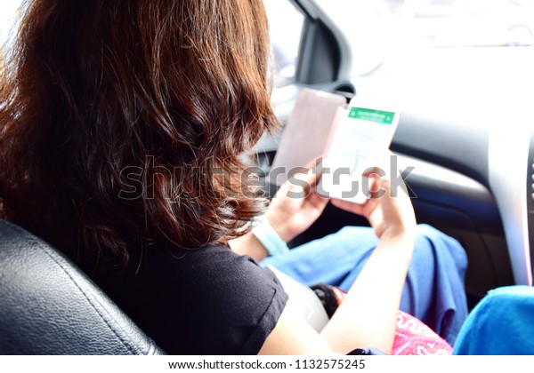 Transportation with technology concept,\
behind of Asian woman long and curly  hair sit in car using wi-fi\
in mobile phone for find the way to\
destination