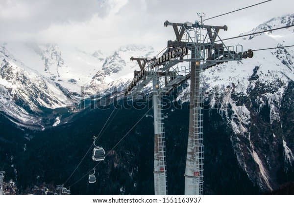 Transportation of tourists in a winter ski\
resort. Metal poles in the form of poles. Beautiful view of the\
snowy mountains and cable car in\
winter.