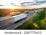 Transportation trucks in high speed driving on a highway through rural landscape. Fast blurred motion drive on the freeway. Freight scene on the motorway