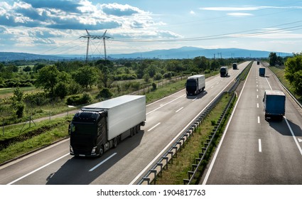 Transportation trucks passing by on a country highway under a beautiful sky. Business Transportation And Trucking Industry.
