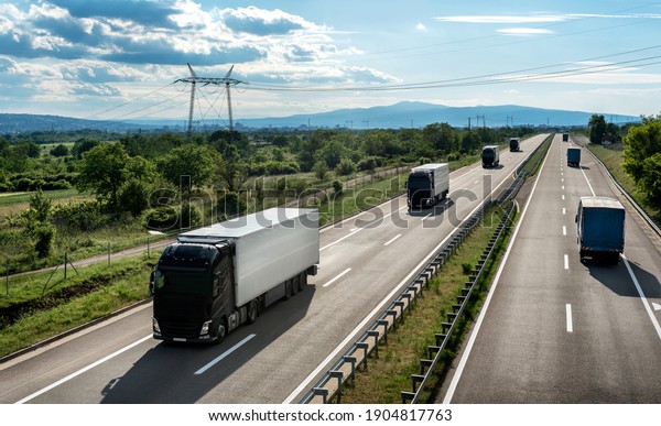 Transportation trucks passing by on a country\
highway under a beautiful sky. Business Transportation And Trucking\
Industry.\
