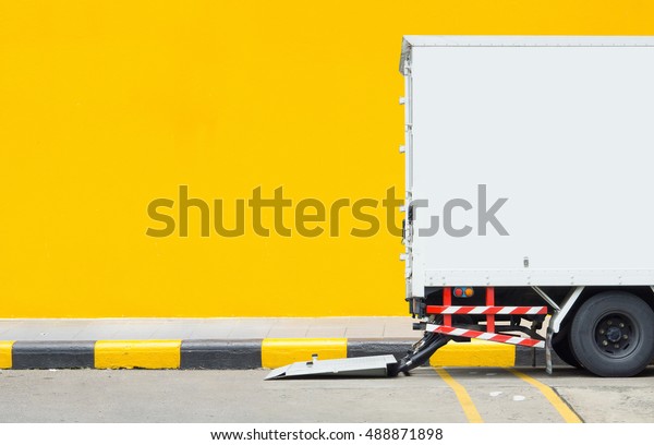 transportation and vehicle concept - Delivery\
truck car parking at footpath with yellow wall background and space\
for text. Use for logistics car\
artwork