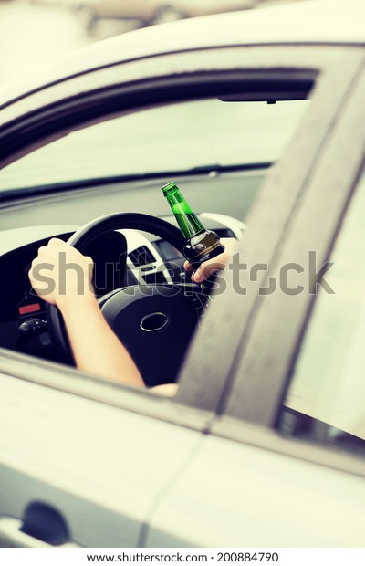 transportation and vehicle concept - man drinking\
alcohol while driving the\
car