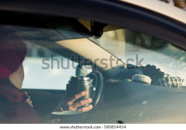 transportation and vehicle concept - man drinking\
coffee while driving the\
car