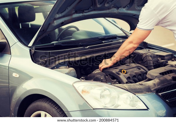 transportation and vehicle concept - man opening car\
bonnet and looking under\
hood