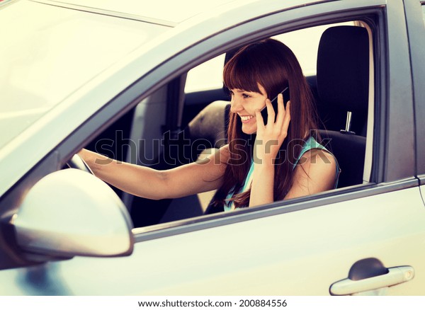 transportation and vehicle concept - woman using\
phone while driving the\
car