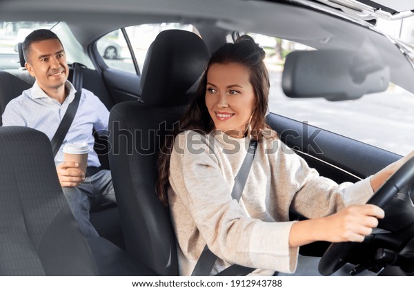 transportation, vehicle and\
people concept - happy smiling female driver driving car with male\
passenger