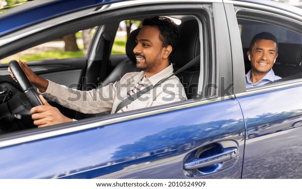 transportation, vehicle and
people concept - happy smiling indian male driver driving car with
passenger