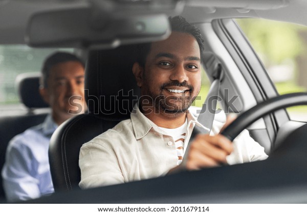 transportation, vehicle and\
people concept - happy smiling indian male driver driving car with\
passenger
