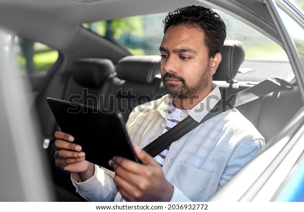 transportation, vehicle and people\
concept - indian male passenger with tablet pc computer in taxi\
car