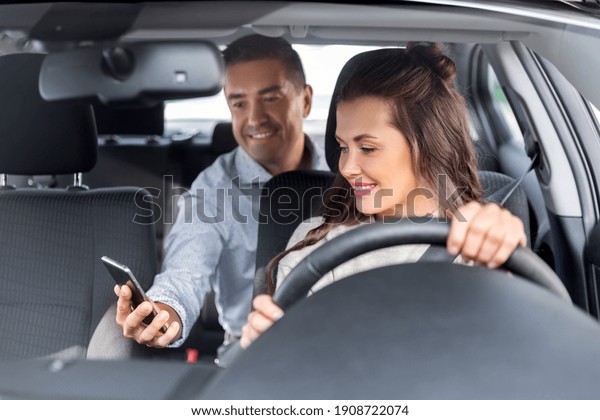 transportation,\
vehicle and people concept - male passenger showing smartphone to\
happy smiling female taxi car\
driver
