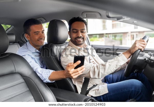 transportation, vehicle and\
technology concept - smiling male passenger showing smartphone to\
car driver