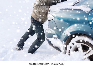 Transportation, Winter, People And Vehicle Concept - Closeup Of Man Pushing Car Stuck In Snow