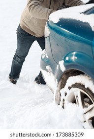 transportation, winter and vehicle concept - closeup of man pushing car stuck in snow
