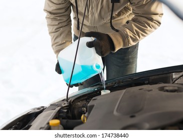 transportation, winter and vehicle concept - closeup of man pouring antifreeze into windscreen water tank