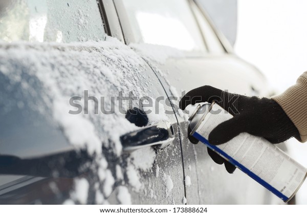 transportation, winter and vehicle concept -\
closeup of man hand with lock door\
de-icer