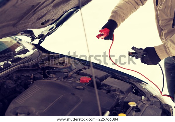 transportation, winter and vehicle concept\
- closeup of man under bonnet with starter\
cables
