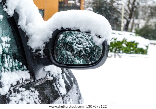 Transportation, winter, weather, vehicle\
concept. Car\'s mirror handle covered in snow and icy rain in\
winter. Blizzard Snowfall icy rain for weather\
concept.