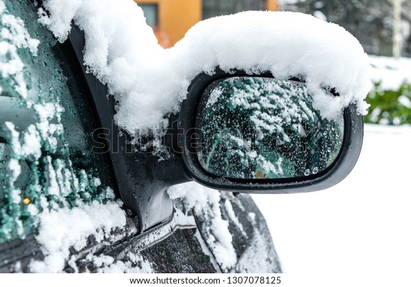 Transportation, winter, weather, vehicle\
concept. Car\'s mirror handle covered in snow and icy rain in\
winter. Blizzard Snowfall icy rain for weather\
concept.