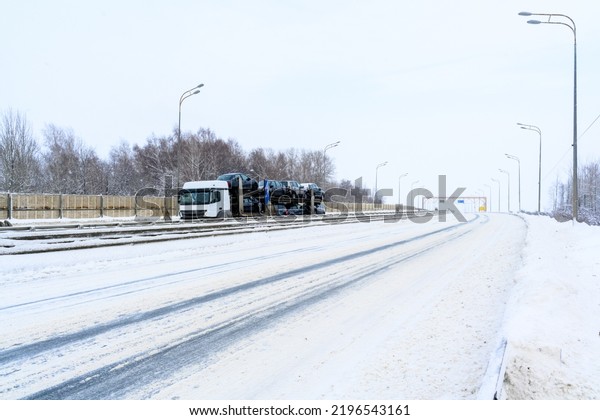 A сar transporter trailer, car carrier,\
semi truck, tractor unit. Cargo transportation in harsh winter\
conditions on slippery, icy and snowy roads.\
