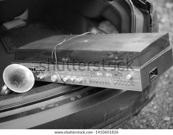 Transporting retro vinyl player in an open car\
boor, in black and\
white