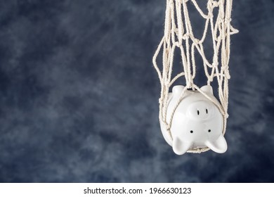 Trapped piggy bank in net on dark background with copy space. Avoid debt traps and speculation. Savings and retirement financial scams
