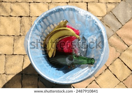 Trash bag with garbage in bin outdoors, top view