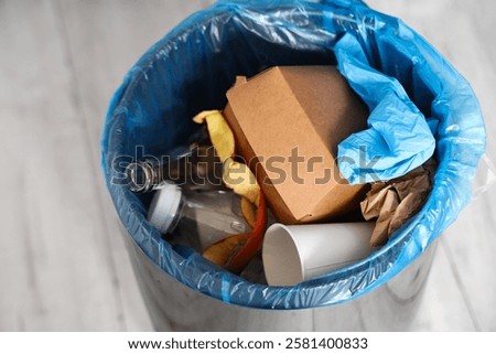 Trash bin full of garbage in kitchen, closeup